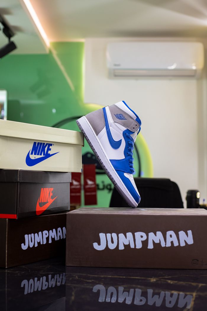 Blue sneakers showcased among branded shoeboxes in a modern setting.