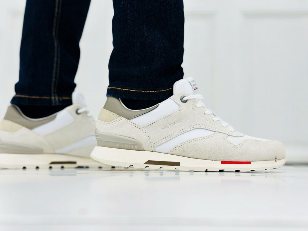 Fashionable close-up of white casual sneakers and jeans indoors.