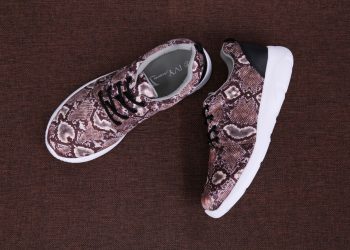 Top view of fashionable snake print sneakers on a textured brown surface, perfect for footwear fashion concepts.